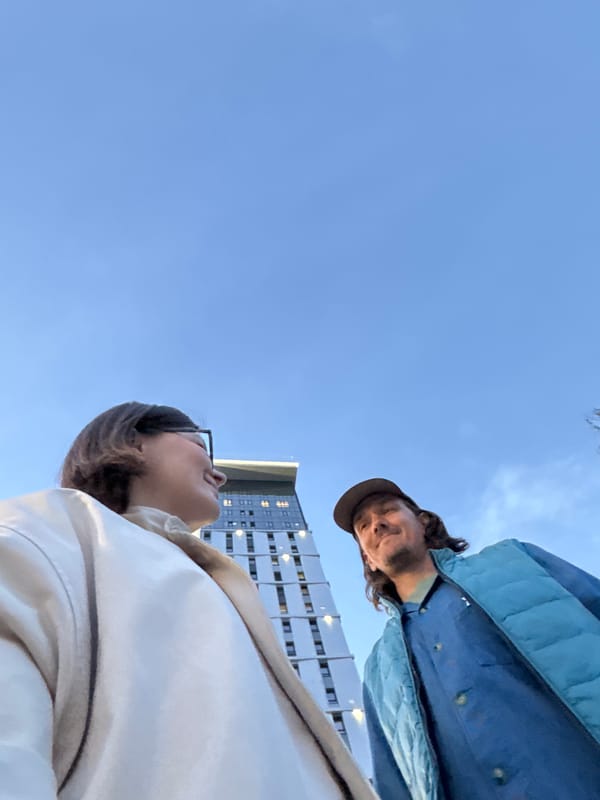 Two people photographed against Izhevsk cityscape at dusk