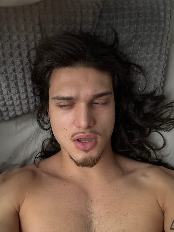 Man with piercings rests in bed in Sofia