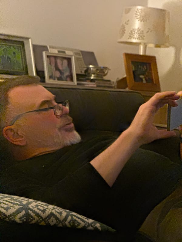 Man with glasses observed resting while holding dark object