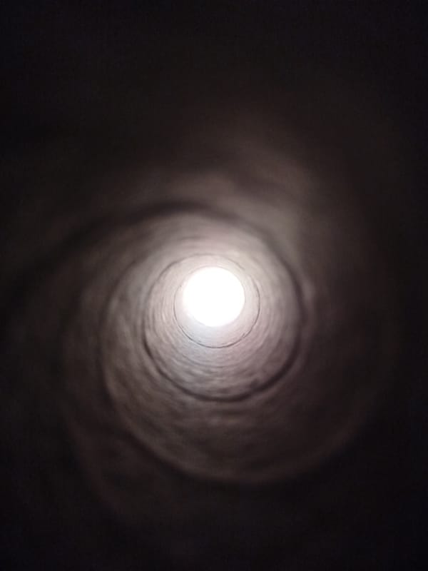 Inside a dark concrete tunnel, light at the end