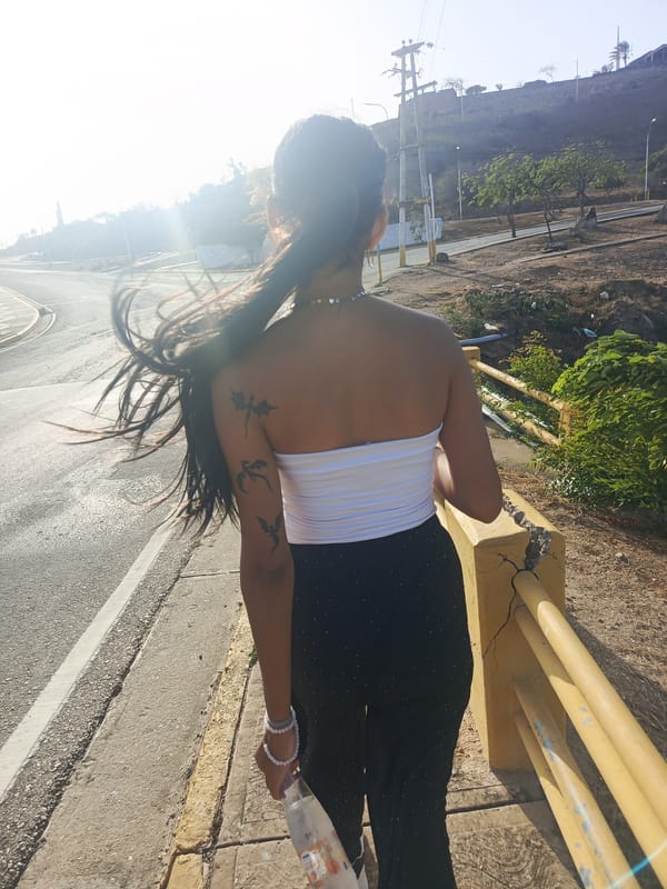 Woman walks coastal road in Juan Griego during sunny evening
