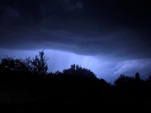 Electric blue-purple light illuminates storm clouds at night