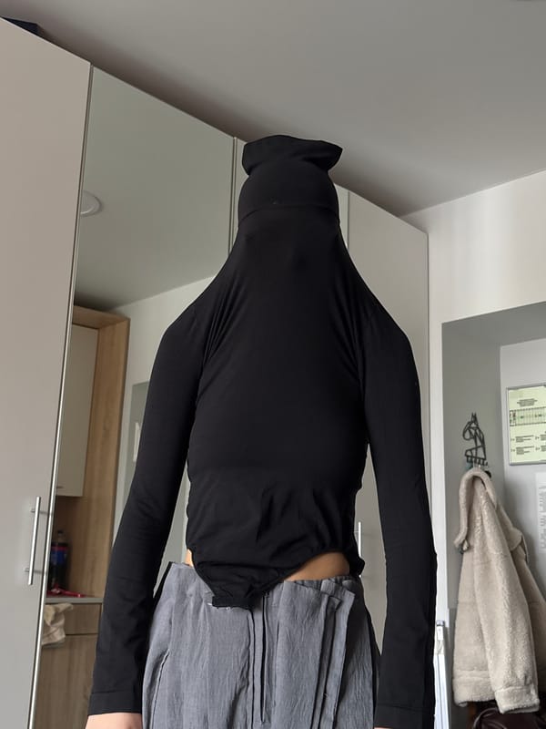 Person in black turtleneck observed at mirrored wardrobe