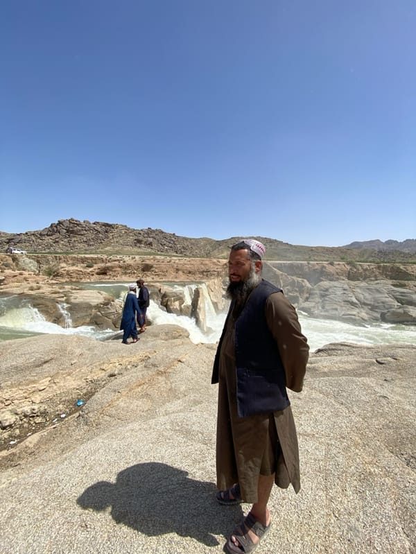 Afghan men visit waterfall in traditional dress