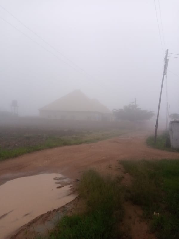 Foggy rural morning: dirt roads, a motorcycle, and a market stall