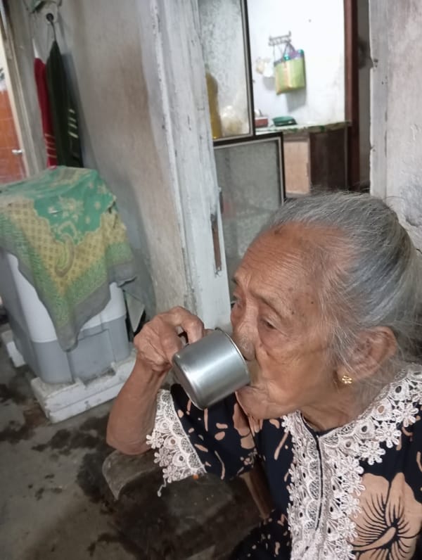 Elderly woman enjoys quiet evening meal in Baron, Indonesia
