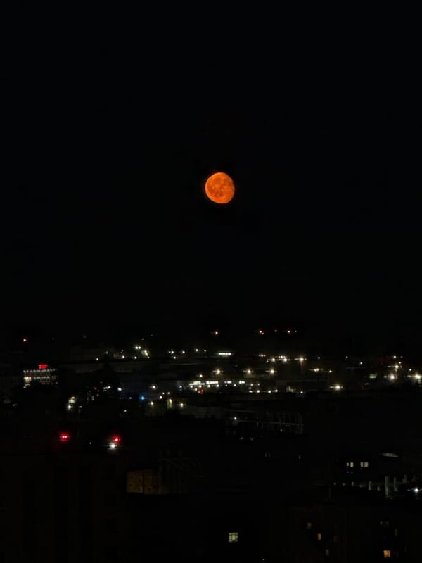 Orange full moon rises over Perm city at night