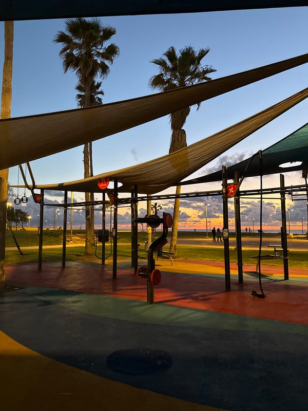 Three people gather on Tel Aviv beach at sunset