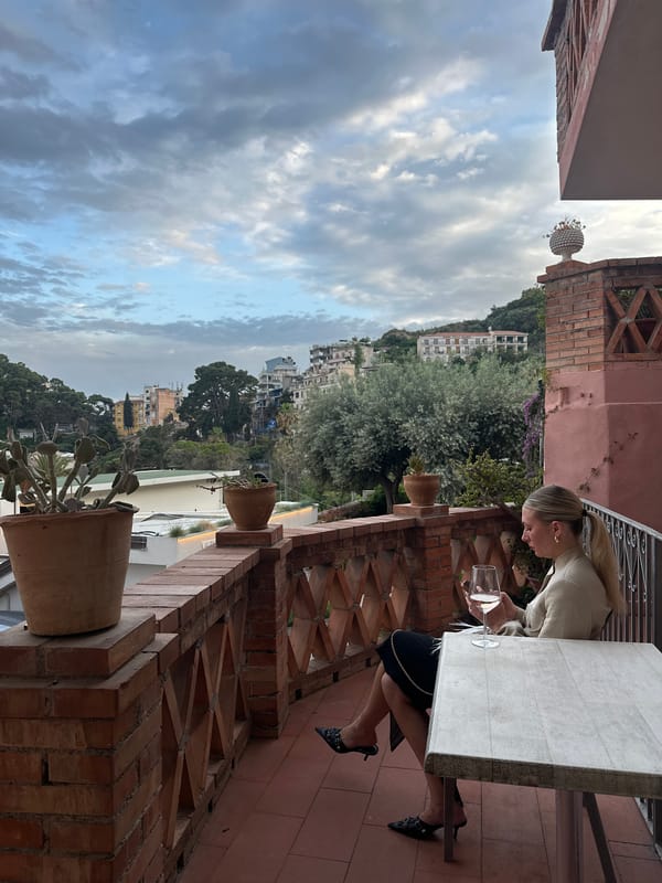 Woman enjoys drink on Taormina terrace overlooking scenic hills