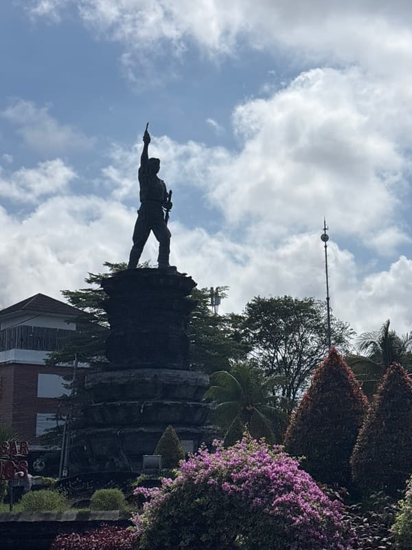 Monument with pointing figure observed in Denpasar park setting