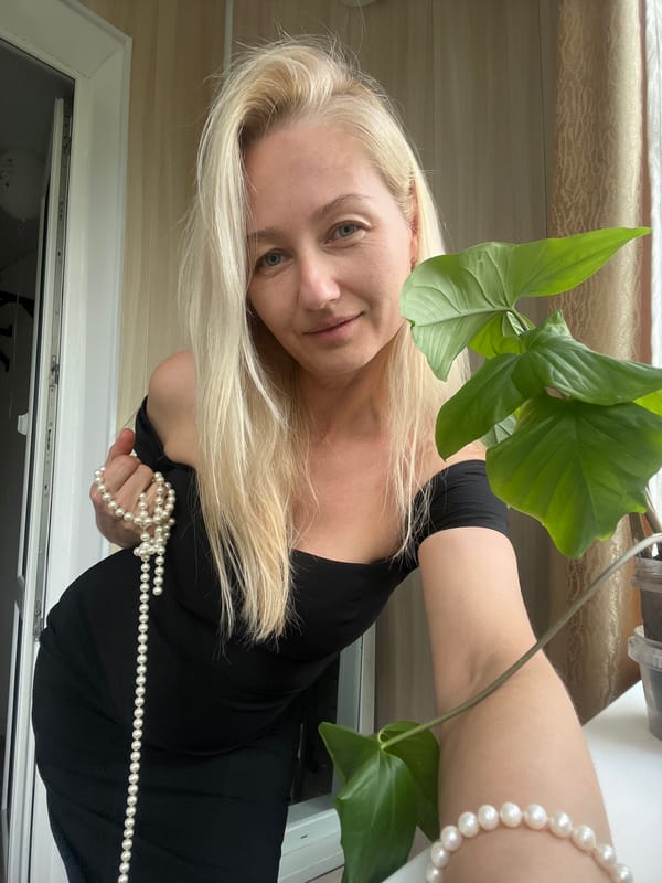 Woman tends plant while holding pearls in Ulyanovsk home