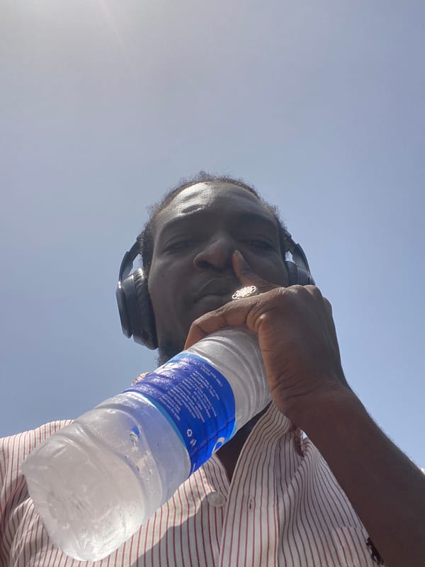 Man with headphones holds water bottle on cracked earth