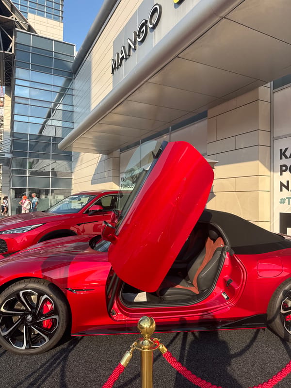 Red MG Cyberster on display near urban commercial district