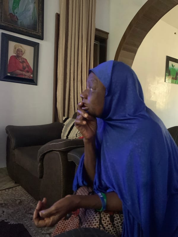 Quiet indoor moment in Jos, blue hijab, hand at mouth