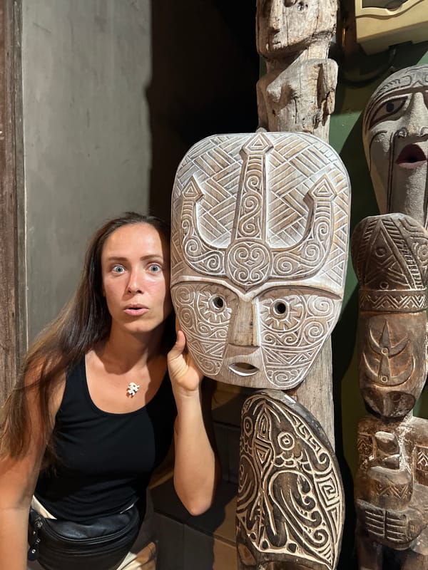 Tourist examines traditional carved masks at Ubud craft display