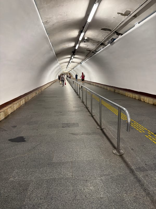 Inside a curved, fluorescent-lit Kyiv metro tunnel