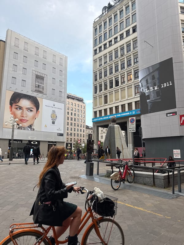 Woman uses phone while on bicycle in Milan street