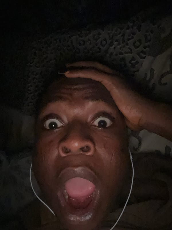 Person photographed showing surprise while lying in bed with headphones