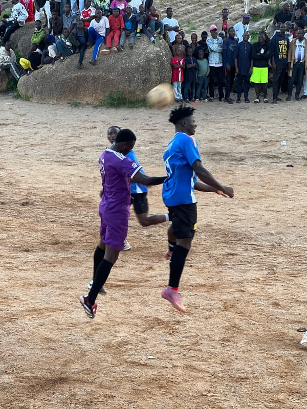 Packed crowd watches local football match on Jos dirt field