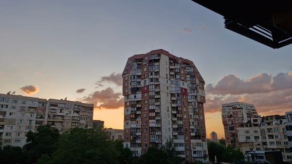 Dusk cityscape captured featuring tall building with rounded red roof