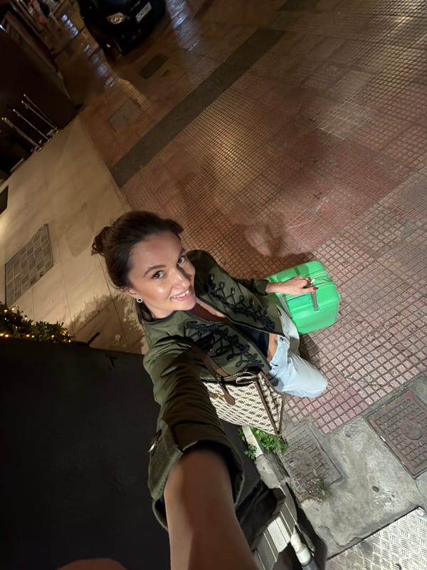 Woman takes nighttime selfie on Athens street with parked scooters