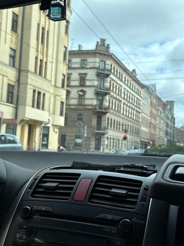 Dashboard-framed view of Riga streets through a car windshield