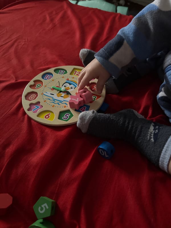 Child plays with wooden clock puzzle in Donetsk