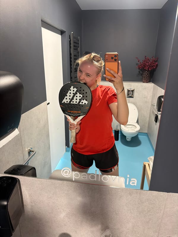 Woman takes bathroom mirror selfies while holding padel racket