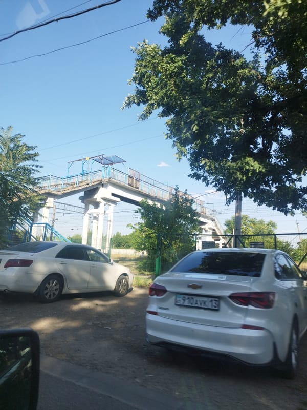 Rolling through Shymkent past rail yards and street-level commerce