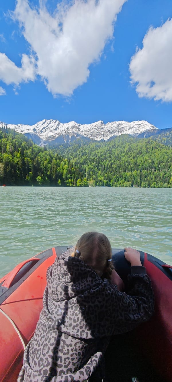 Children enjoy boating on Abkhazian lake under sunny skies