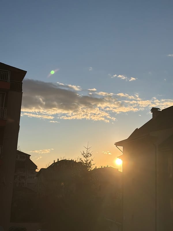 Dawn breaks over Sofia skyline, buildings silhouetted against bright sun