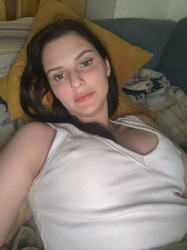 Relaxed close-up selfie on a bed, casual indoor setting.