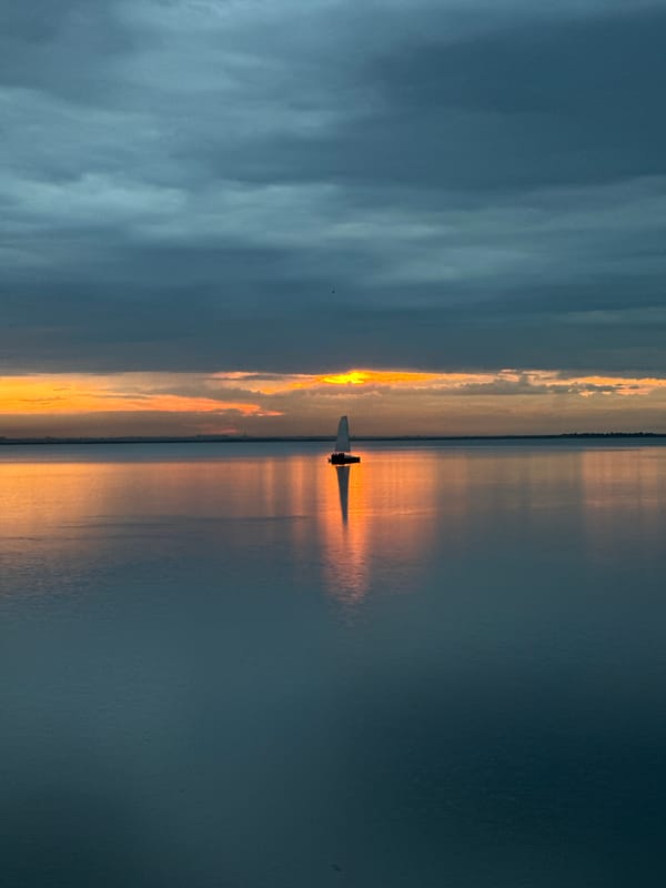Stormy sunset over a Kokshetau lake, sailboat on calm water