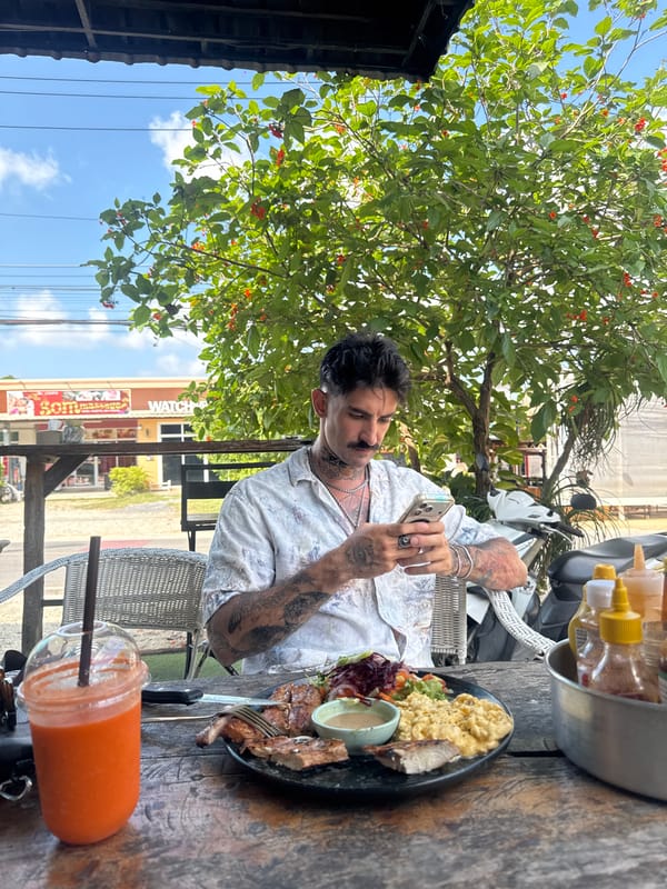 Man photographs food at outdoor table in Chalong, Thailand