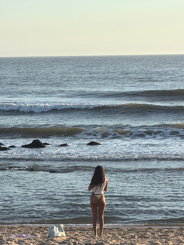 Woman photographs ocean sunset at Portugal beach