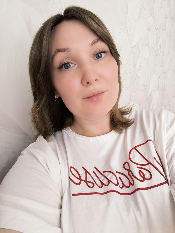 Woman takes indoor selfie wearing white shirt with red text