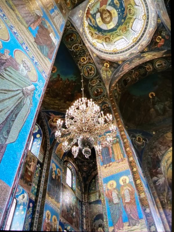 Tourist visits Saint Petersburg's Church of Spilled Blood, Aurora cruiser