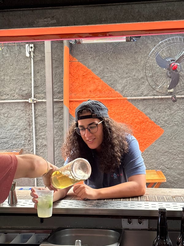 Person pours drink for another in São Paulo indoor gathering
