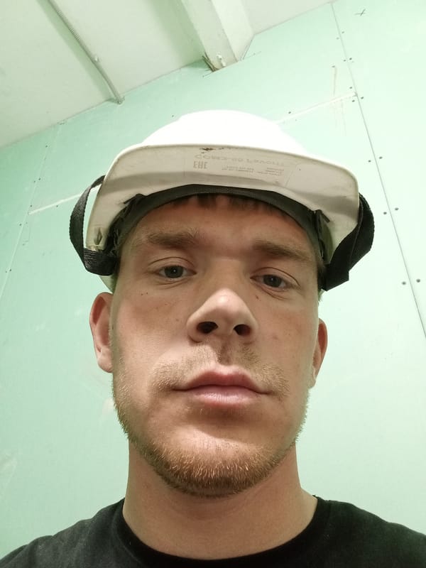 Construction Worker in White Hard Hat Photographed Against Green Wall