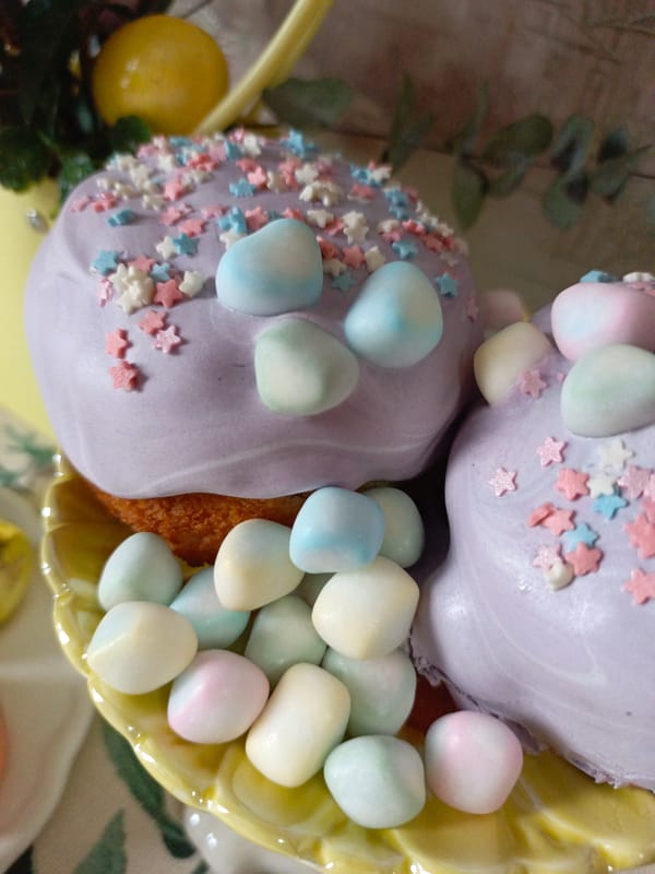 Purple-frosted cupcakes with pastel decorations spotted on yellow plate