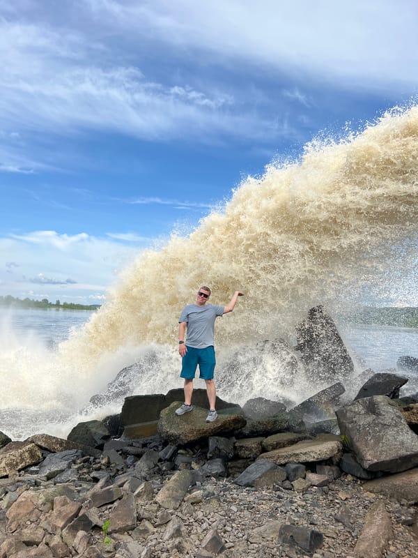 Man poses at powerful spillway waterfall in Chernushka, Russia
