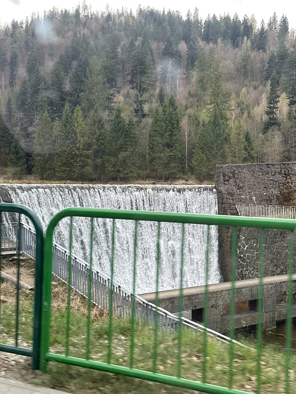 Water flows over dam in forested Wisła, Poland