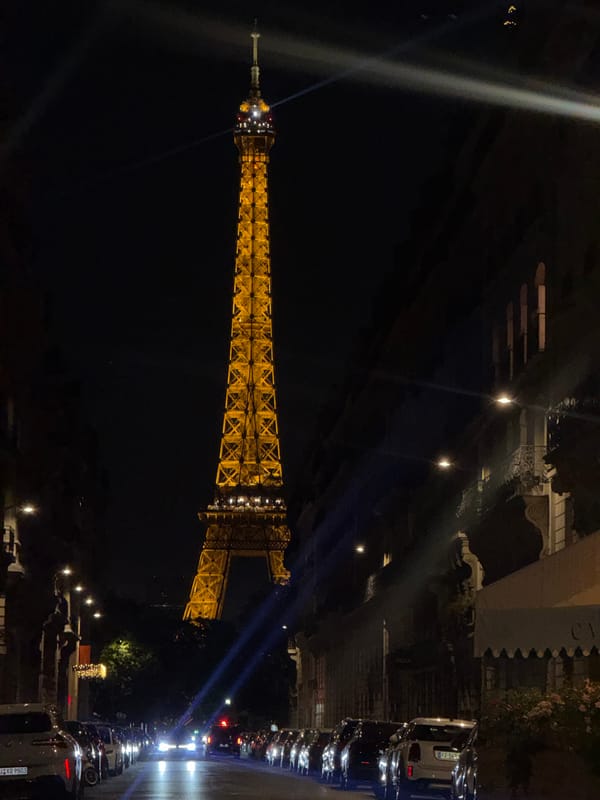 Eiffel Tower glowing gold with searchlights at night