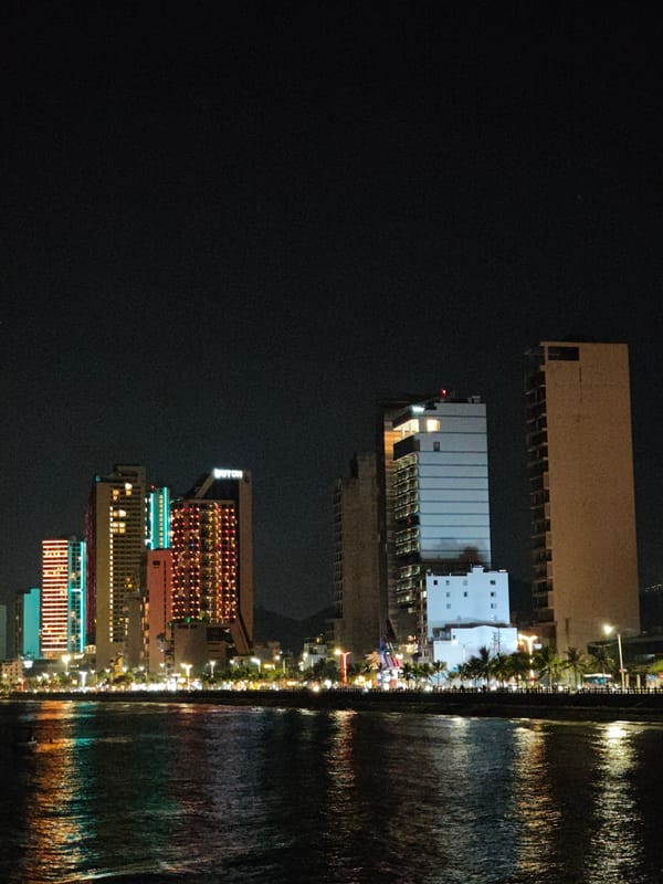 Illuminated waterfront buildings observed in nighttime cityscape