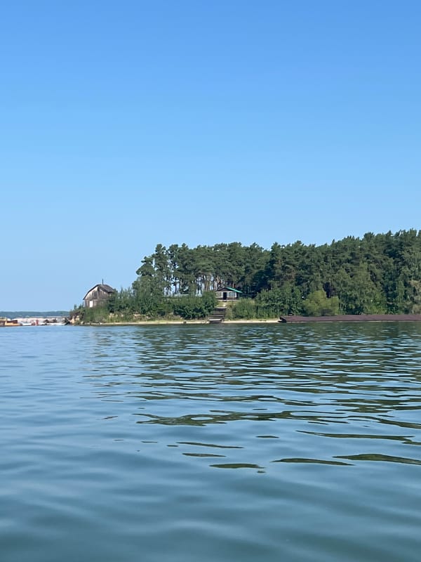 Calm Russian waterway, beached barge, and a motorboat out on the water