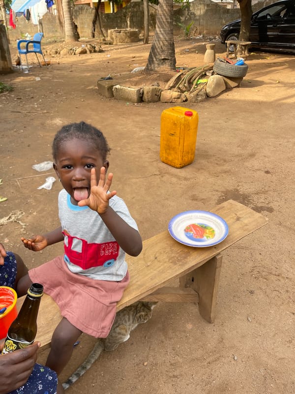 Child fed by caregiver on wooden bench in Akwanga
