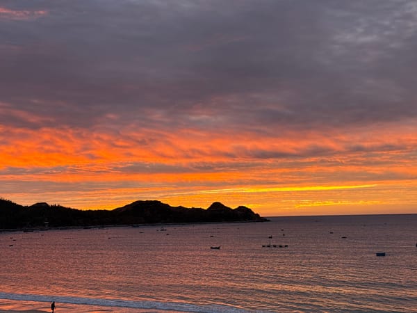 Sunset over a calm beach, sky shifting through vivid colors