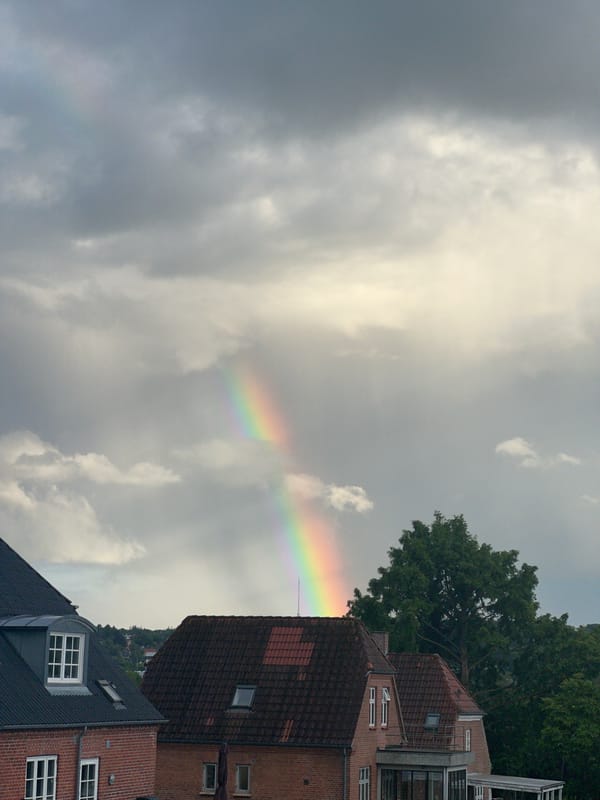 Rainbow over Vejle residential area through stormy clouds