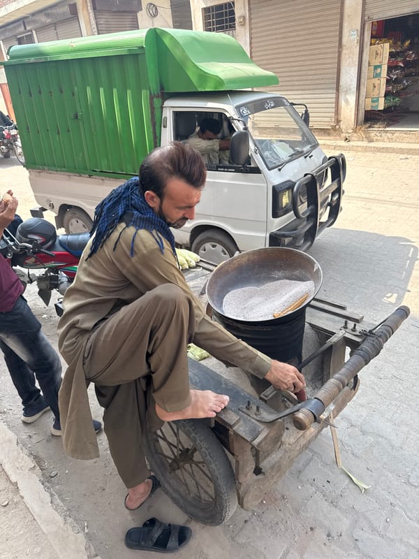 Street vendor roasts corn in sand-filled bowl in Multan