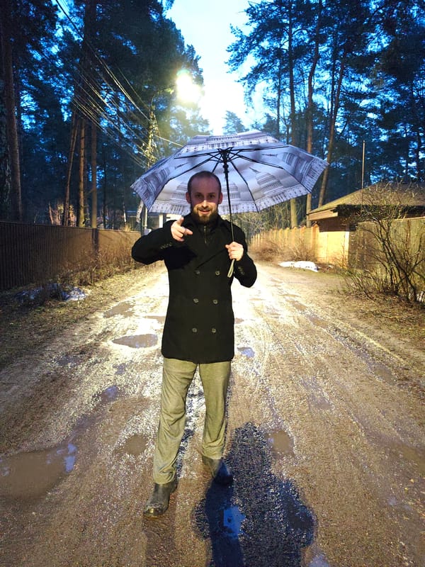 Man with American flag umbrella stands on muddy Russian street